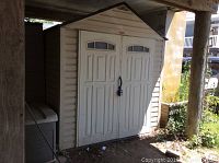 Front exterior view of shed under deck showing double doors with padlock