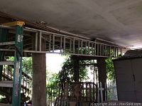 Full view of the extension ladder leaning horizontally under a porch roof, showing its length and frame.