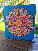 Front cover showing blue binder with multicolor flower and ladybug design