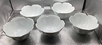 Five white scalloped bowls top view