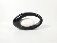 Front view of glossy black o-shaped vase with white insert