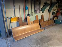 Two detached wooden church pew benches with legs and tools visible