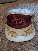 Front of cap showing HONGO FIRE VOLUNTEER embroidery and gold leaf design on brim