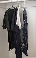 Six tops hung on hangers showing variety and condition