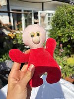 Front view of small red and pink plush toy held in hand