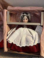 Doll in original box with burgundy dress and white apron