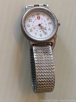 Front full watch view showing white dial with Swiss Army logo, green luminescent numbers, and silver band.