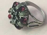 Side angle showing the sterling silver ring band and the floral cluster design with red stones.