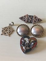 Photo showing the full set of silver jewelry with pendant, earrings, and two brooches.