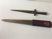 Two vintage letter openers laid flat on a white surface, showing their full length and handle designs.