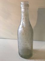 Full view of the clear glass Coca-Cola bottle showing straight sides and minor surface wear.
