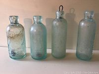 Four aqua green John Verner bottles showing their size and shape variations, appearance and condition.