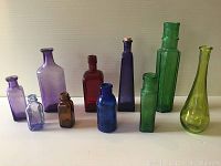 Full view of all ten colourful vintage bottles in a row showing their colours and relative sizes.