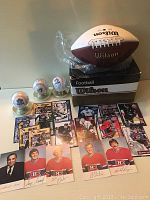 Wide view showing Wilson NFL football on box, Kraft Dinner hockey cards spread out, and three Toronto Blue Jays souvenir baseballs on display stands.