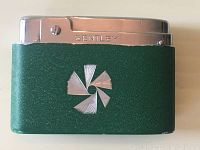 Front view of green textured lighter with chrome top and Bentley engraving; shows central decorative emblem and wear.