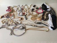 Photo showing all necklaces and watches arranged on a flat surface, highlighting variety in styles and materials.