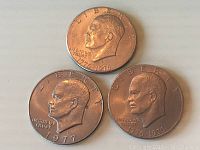 Obverse side of the three US dollar coins showing dates 1976, 1977, and 1776-1976 bicentennial date with Liberty Bell and Eisenhower portraits.