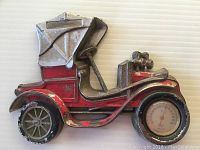 Front side view of the metal thermometer shaped as a vintage Peugeot car showing red and silver paint, spoked wheels, and the round thermometer in the front right wheel area.