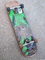 Bottom view showing worn green graphics, trucks, wheels