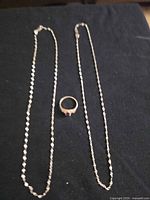 Necklace and ring laid flat on dark background