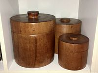 All three teak canisters grouped to show graduated sizing and lids