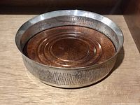 Full view of sterling silver wine coaster showing textured sides and wooden base