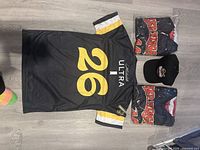 Back view of jersey showing number 26, Michelob Ultra logo, packaged Red Wings T-shirt and cap