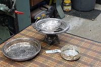 Group shot of round tray, footed compote, pierced coaster with tongs