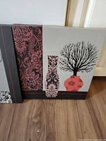 Front view of one canvas showing grey background, red vase with floral damask, black tree silhouette