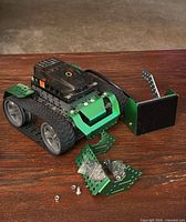 Front view of assembled tracked robot, extra brackets, screws and nuts on table