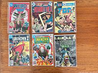 Group shot of six bagged DC comic books laid out on wood surface