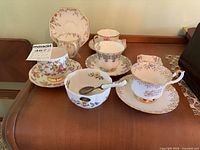 Group of teacups, saucers, bowl and spoon displayed on surface