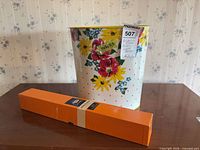 Wastebasket with floral design next to boxed cushion