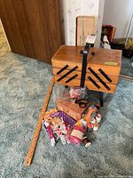 Closed wooden accordion sewing box with yardstick and loose sewing items