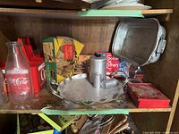 Shelf with Coca-Cola bottle & carrier, Mirro cookie press box, cookie cutters box, aluminum tray with canister and shakers