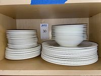 Stacked plates, saucers and bowls within cabinet