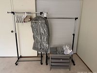 Two rolling garment racks, hangers, garment bag, Elfa organizer, folded items