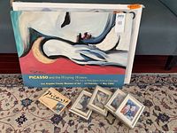 Front view showing Picasso poster, stack of posters behind, four small framed prints, Picasso postcard book