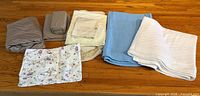 All bedding items laid out showing sheet sets, floral sheet, extra fitted sheet, blankets