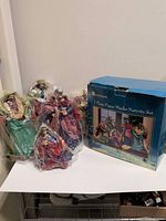 Group view of five wrapped paper mache nativity figurines beside original box