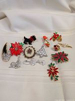 All twelve assorted holiday brooches displayed on fabric
