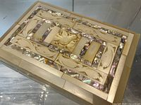 Top view of rectangular wooden box showing carved center panel and surrounding mother of pearl inlay