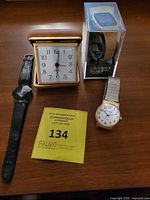 All four items grouped: Rhythm watch, travel alarm clock, Phaser digital watch in box, gold-tone analog watch