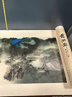 Overall view of partially unrolled scroll showing landscape painting and rolled end with inscription
