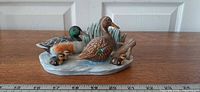 Full view of ceramic duck family figurine with ruler for scale