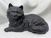 Front view of black cast iron cat with green eyes