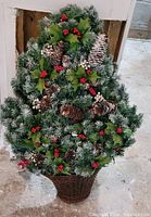 Front view of flocked artificial Christmas tree showing pinecones, berries, basket