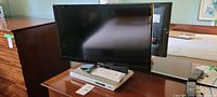 Samsung flat panel TV on top of Memorex DVD player with paperwork visible