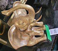 Front angled view of brass elephant figurine showing raised trunk and patina