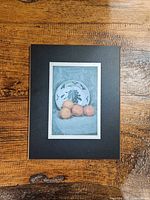 Full view of framed matted still life print on wooden surface
